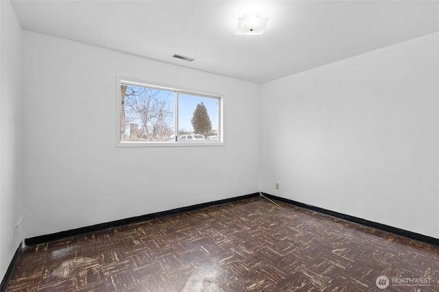 empty room with visible vents, baseboards, and dark floors