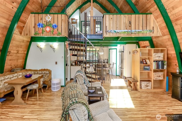 living room featuring high vaulted ceiling, wood finished floors, wooden ceiling, wood walls, and stairs