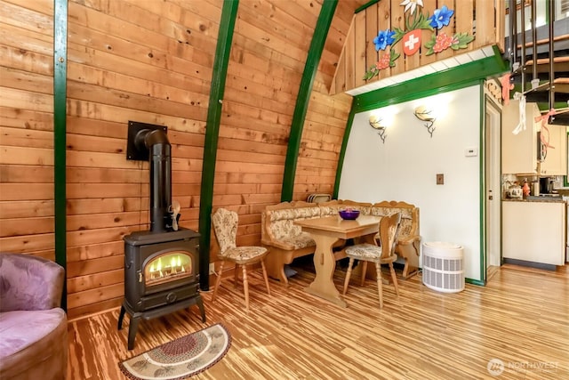 interior space featuring wooden walls, wood ceiling, wood finished floors, and a wood stove