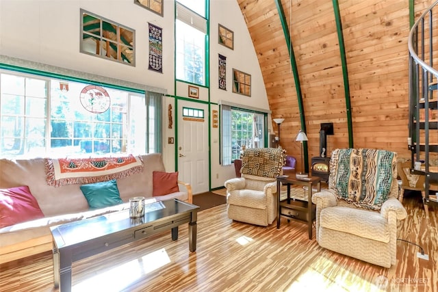 living area with high vaulted ceiling, wood finished floors, stairway, wooden ceiling, and a wood stove