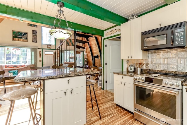 kitchen with stainless steel electric range oven, decorative backsplash, white cabinets, black microwave, and a kitchen breakfast bar