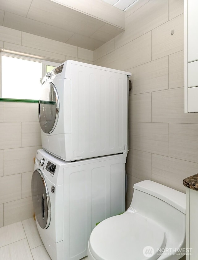 laundry area featuring laundry area, tile walls, and stacked washer and dryer