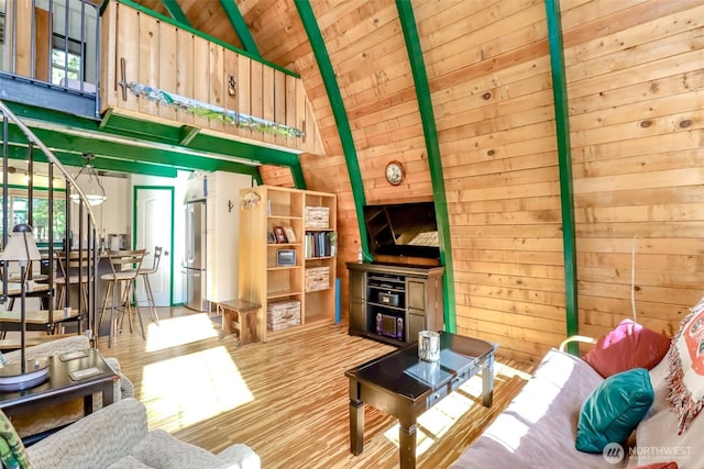 living room featuring stairs, wooden walls, wood ceiling, and high vaulted ceiling