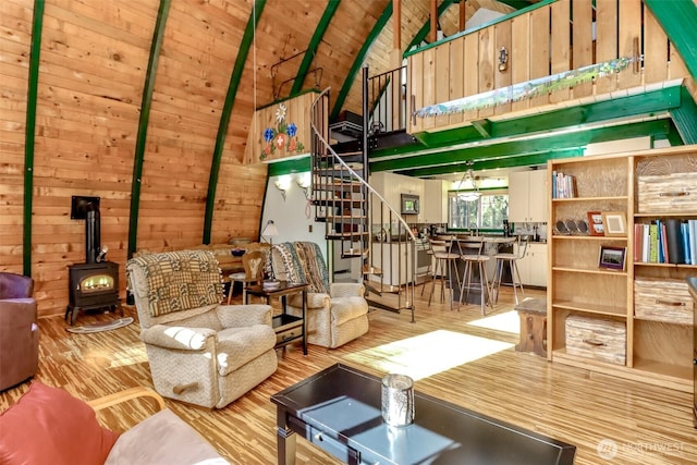 living room with wooden walls, stairs, wooden ceiling, a wood stove, and wood finished floors