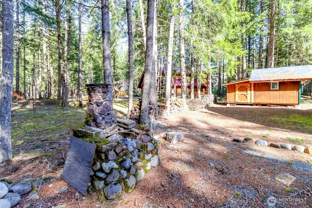 view of yard featuring a wooded view, a storage unit, and an outdoor structure