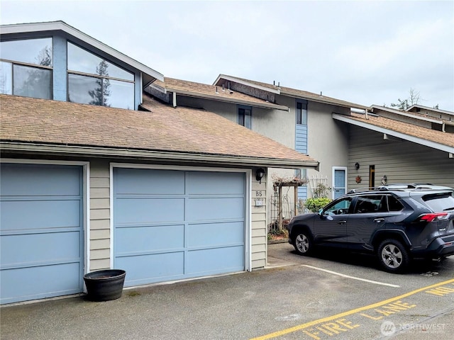 view of front facade featuring a shingled roof and a garage