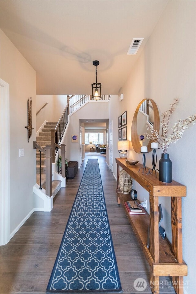 entryway with visible vents, baseboards, wood finished floors, and stairs