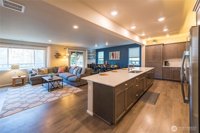 kitchen with visible vents, light countertops, freestanding refrigerator, wood finished floors, and a sink