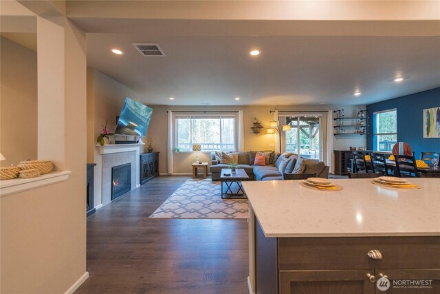 kitchen with a healthy amount of sunlight, visible vents, dark wood-style flooring, and a tile fireplace