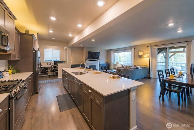 kitchen featuring dark wood-type flooring, a sink, gas range oven, freestanding refrigerator, and dishwasher