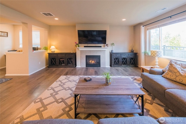 living room with wood finished floors, visible vents, baseboards, a fireplace, and recessed lighting