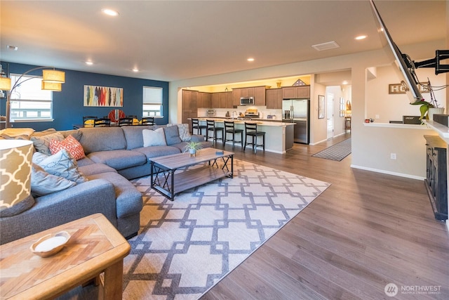 living room featuring recessed lighting, visible vents, baseboards, and wood finished floors