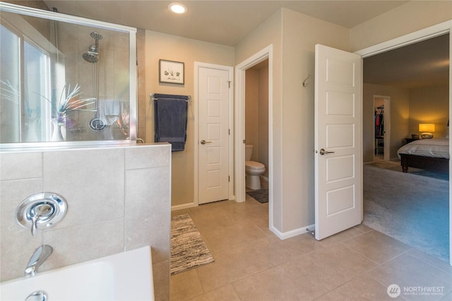 full bathroom featuring tile patterned floors, toilet, baseboards, and a tile shower