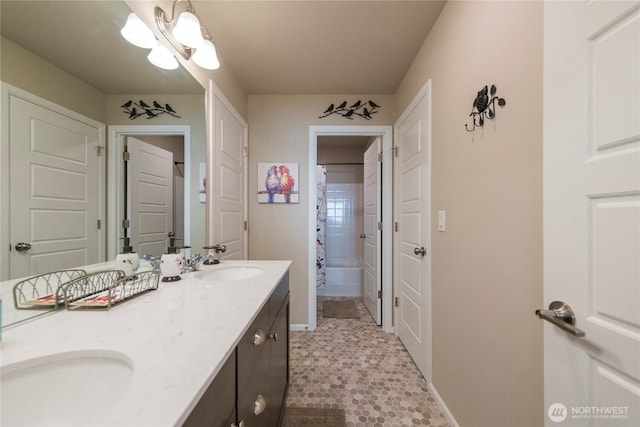 bathroom with double vanity, shower / bathtub combination with curtain, baseboards, and a sink