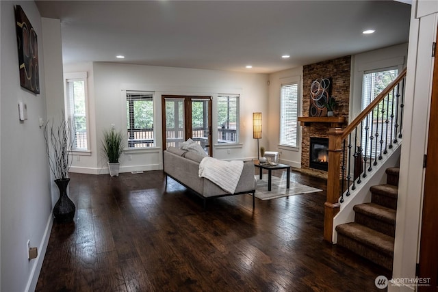 living room with dark wood-style floors, a healthy amount of sunlight, a fireplace, and stairs