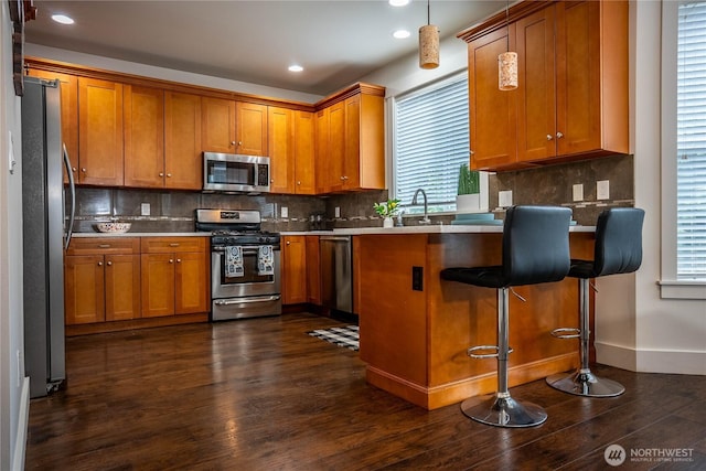 kitchen with brown cabinetry, dark wood finished floors, and stainless steel appliances