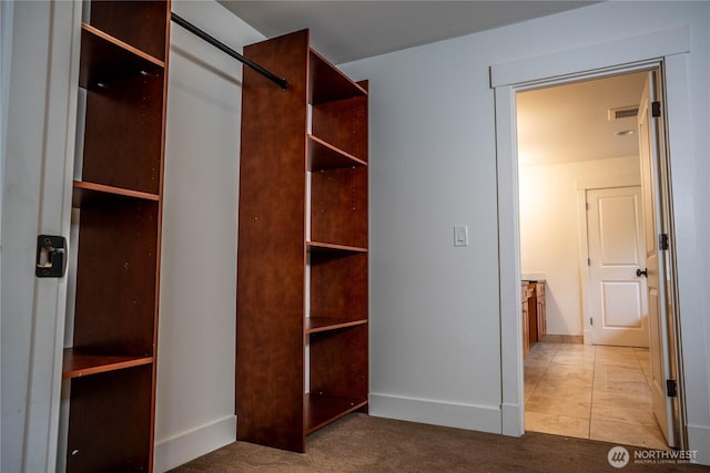 walk in closet featuring light carpet, light tile patterned floors, and visible vents