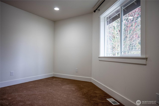 spare room with dark colored carpet, visible vents, baseboards, and recessed lighting