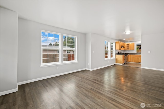 unfurnished living room featuring baseboards and dark wood finished floors