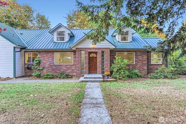 view of front facade featuring brick siding, a front lawn, metal roof, and a standing seam roof