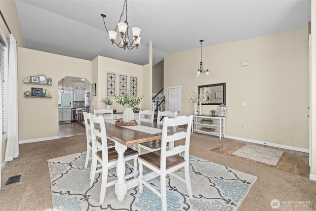 dining space with visible vents, stairway, lofted ceiling, arched walkways, and a notable chandelier