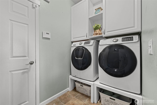 laundry room featuring washer and dryer, baseboards, and cabinet space