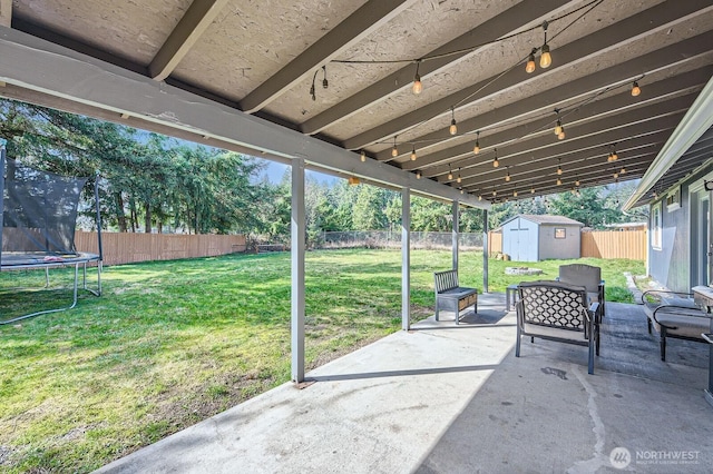 view of patio with a fenced backyard, a storage unit, a trampoline, and an outdoor structure