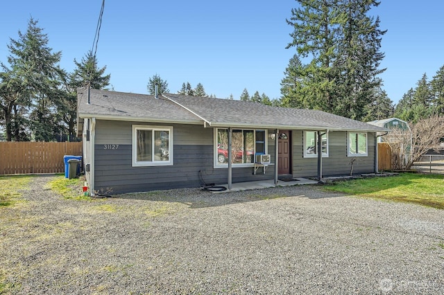 ranch-style home with cooling unit, fence, and a shingled roof