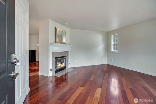 unfurnished living room featuring baseboards, wood finished floors, and a fireplace