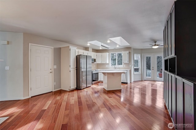 kitchen featuring light wood-style flooring, appliances with stainless steel finishes, a center island, and light countertops