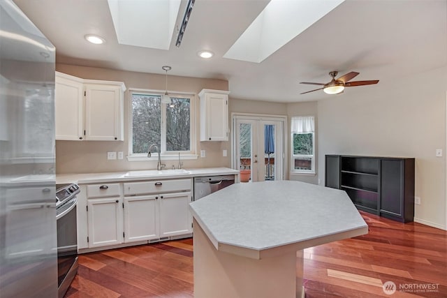 kitchen with a skylight, light wood-style flooring, stainless steel appliances, a sink, and light countertops