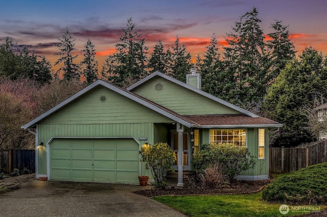 view of front of house featuring fence, roof with shingles, driveway, a chimney, and a garage