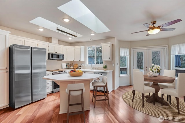 kitchen featuring a sink, a kitchen island, appliances with stainless steel finishes, and a skylight