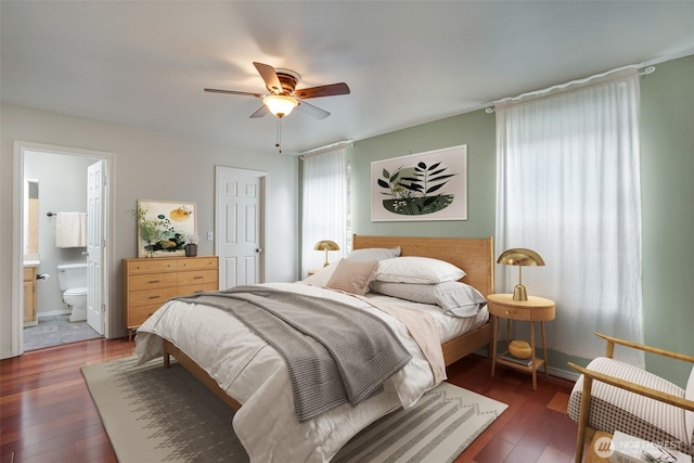 bedroom featuring ensuite bath, a ceiling fan, baseboards, and hardwood / wood-style floors