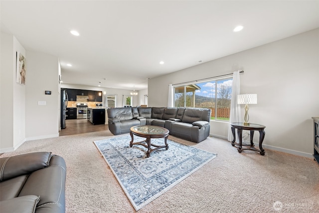 living room with recessed lighting, baseboards, light colored carpet, and an inviting chandelier