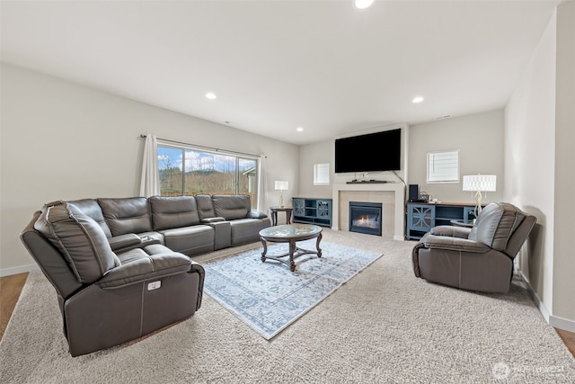 living room with a glass covered fireplace, recessed lighting, and baseboards