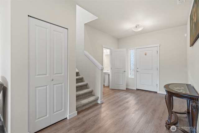 foyer with stairway, baseboards, and wood finished floors