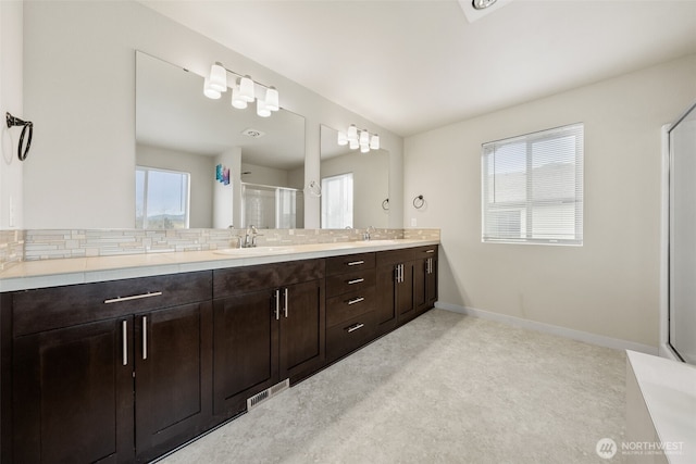 bathroom featuring an enclosed shower, visible vents, baseboards, and a sink