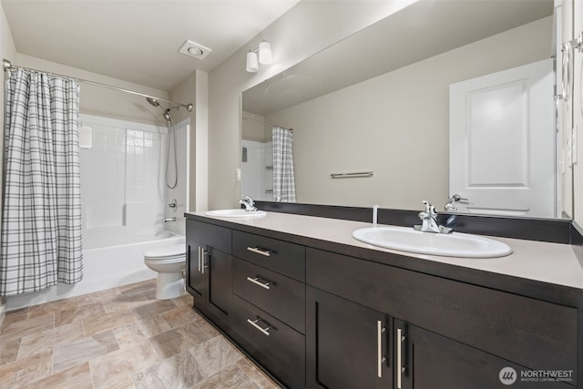 bathroom featuring toilet, double vanity, shower / bath combination with curtain, and a sink