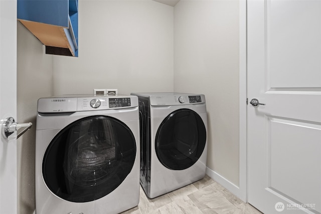 washroom featuring washer and clothes dryer, laundry area, and baseboards