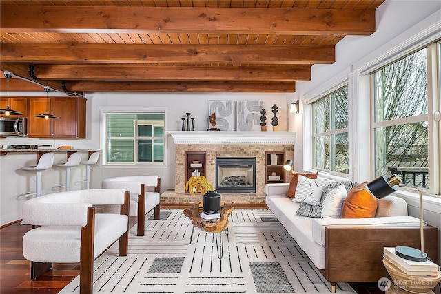 sunroom featuring wooden ceiling, beamed ceiling, and a fireplace