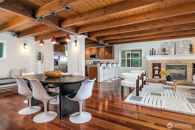 dining space featuring beam ceiling, a fireplace, wood ceiling, and dark wood-style flooring