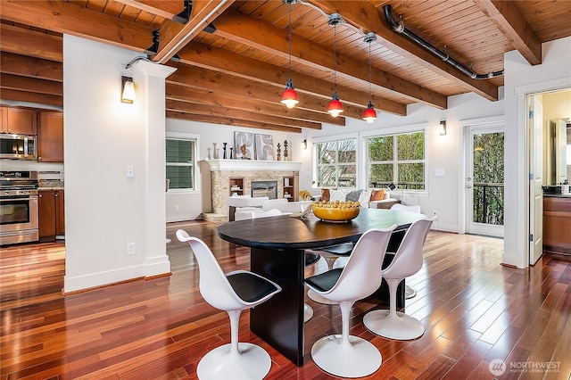 dining room with baseboards, a multi sided fireplace, beamed ceiling, wooden ceiling, and dark wood-style flooring