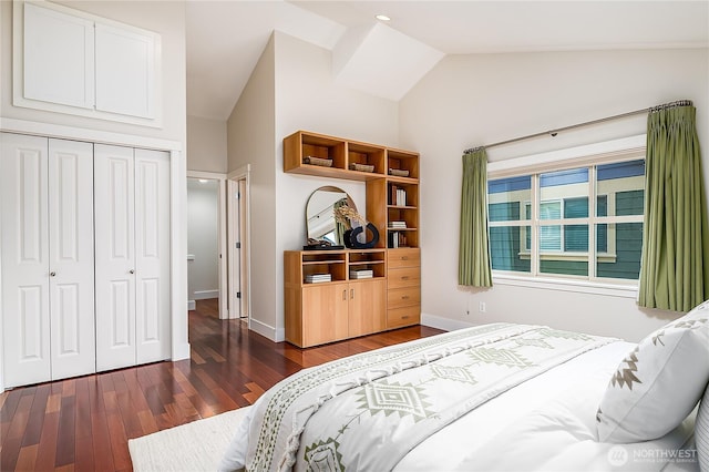 bedroom with vaulted ceiling, wood finished floors, a closet, and baseboards