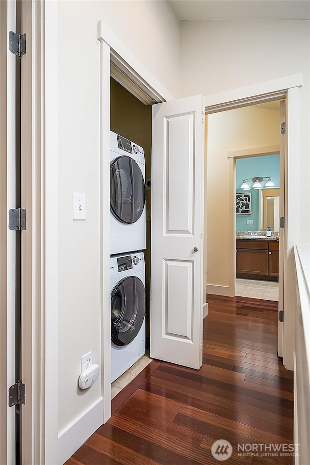 laundry area with laundry area, stacked washing maching and dryer, and hardwood / wood-style flooring