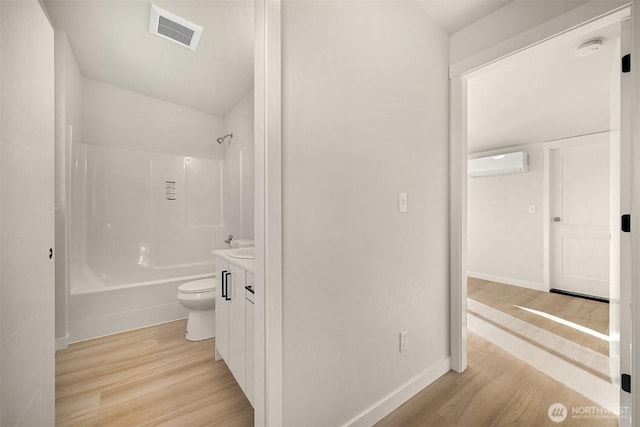 bathroom featuring vanity, wood finished floors, visible vents, a wall mounted AC, and toilet