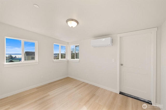 empty room featuring baseboards, wood finished floors, and a wall mounted AC