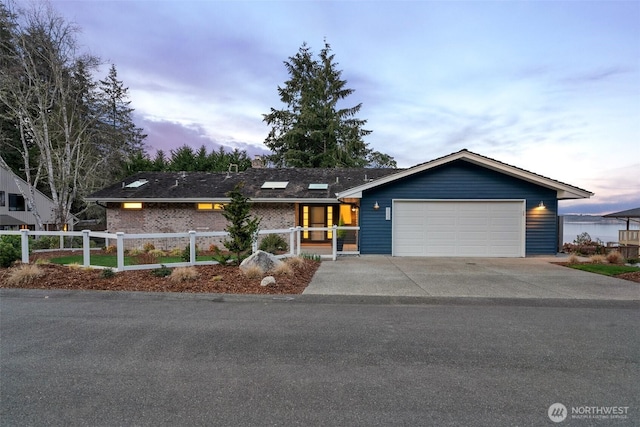 view of front of house with a fenced front yard, driveway, brick siding, and a garage