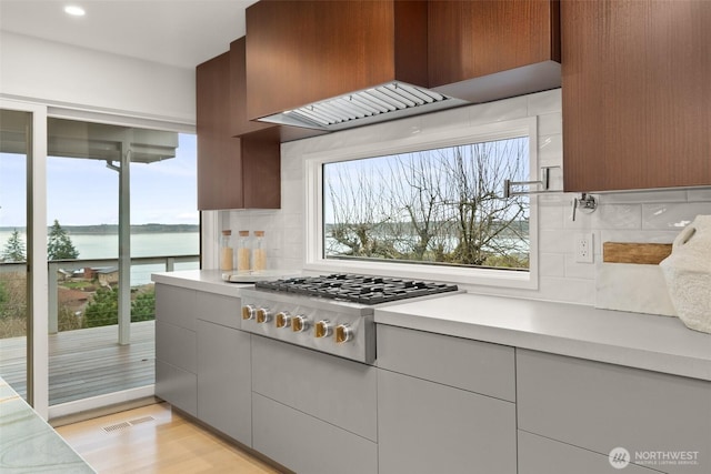 kitchen featuring light countertops, ventilation hood, plenty of natural light, and stainless steel gas cooktop