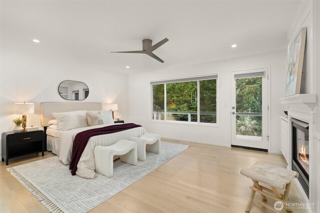 bedroom featuring recessed lighting, light wood finished floors, and a large fireplace